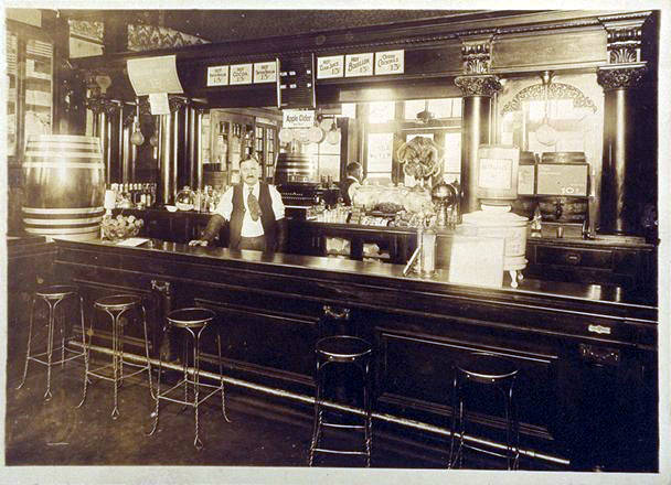 Charles Peterson, bartender, posed behind the bar of Rehfeldï¿½s Place, located at Main and Lincoln (now El Camino Real and California Avenue), 1923